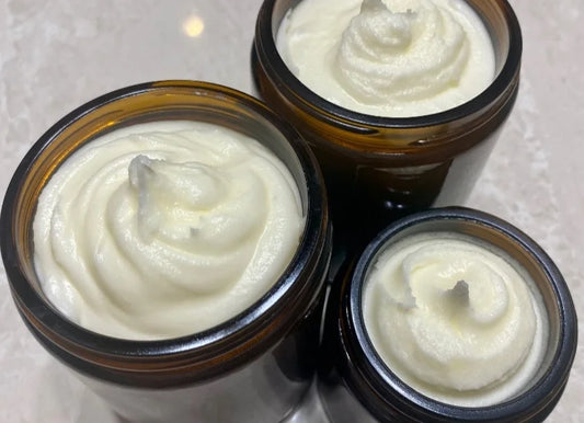Three open amber jars filled with Crushed Botanicals Apothecary Whipped Tallow Butter are arranged on a light-colored surface. The jars appear to contain a lotion or cream with a thick, smooth texture and small peaks of the product in the center.